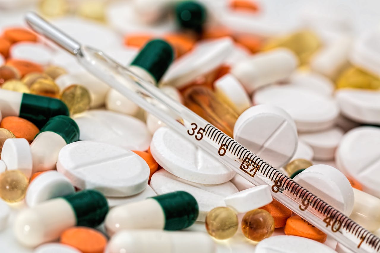 Close-up image showing various pills and a thermometer, emphasizing health and medicine.